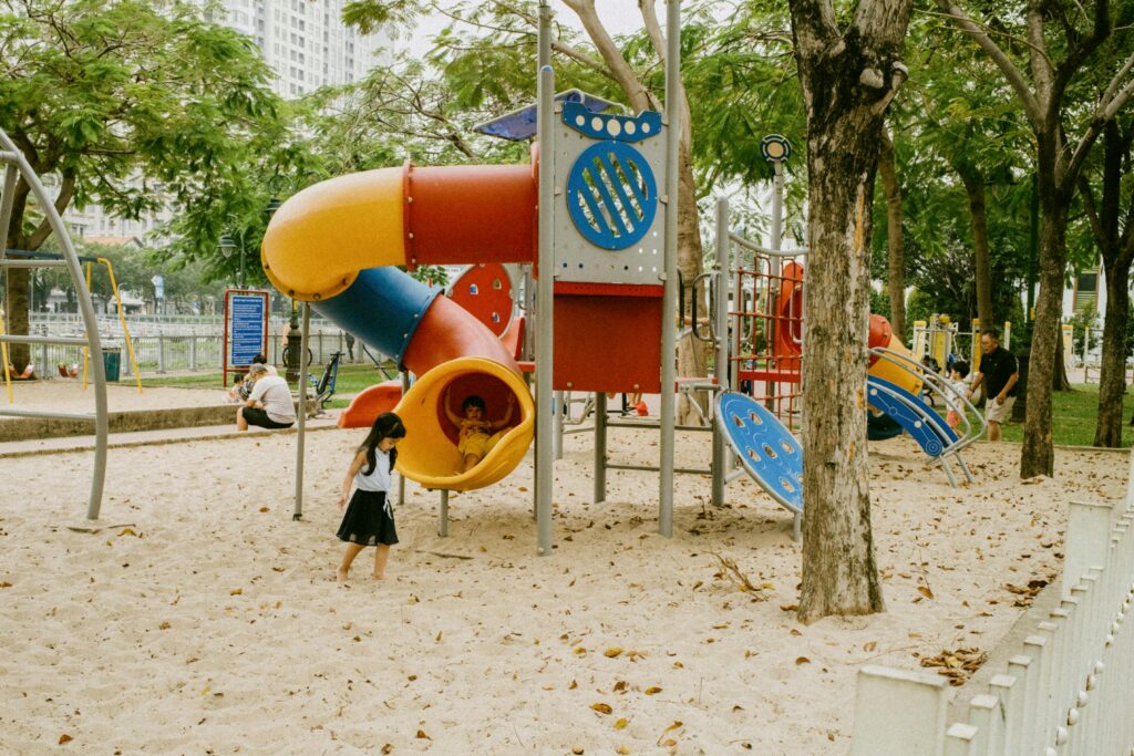 Kids enjoying colorful slides and play structures in an outdoor park playground.